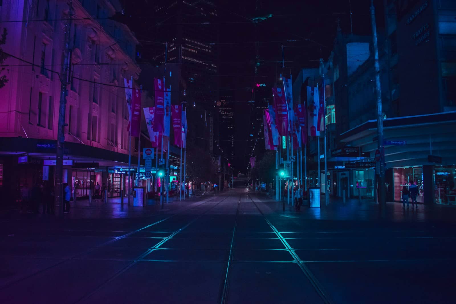 A city street at night, lit by signs and screens