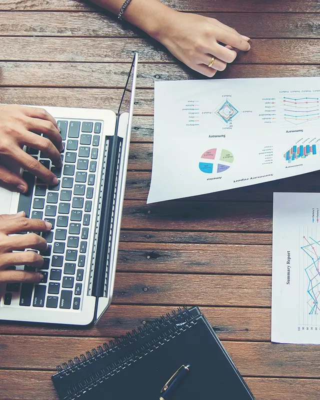 A planning session: a laptop and printed charts on a wooden table